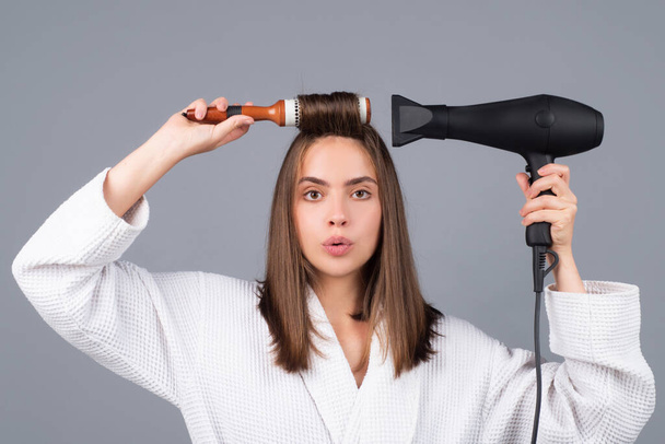 Woman combing hair. Portrait of female model with hair dryer. Girl with hairbrush, hair care and beauty. Morning routine. - Foto, Bild