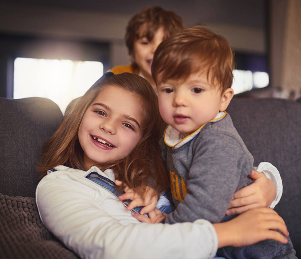 ¿No es el más lindo? Retrato recortado de una adorable niña y sus dos hermanos en su sala de estar en casa. - Foto, Imagen