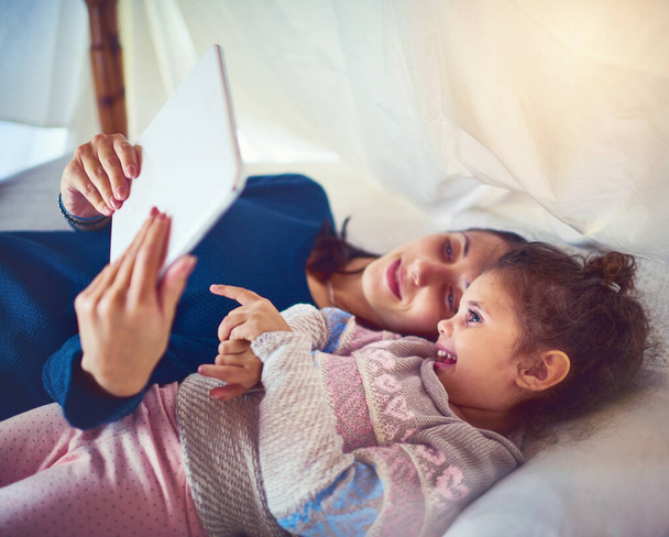 Interaktive Lernzeit. Aufnahme einer Mutter und ihrer kleinen Tochter mit einem digitalen Tablet zu Hause. - Foto, Bild