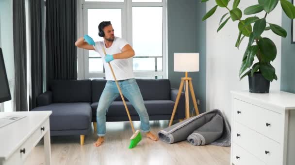 Muž uklízí dům a baví se tancováním s koštětem. Zpomalený pohyb - Záběry, video