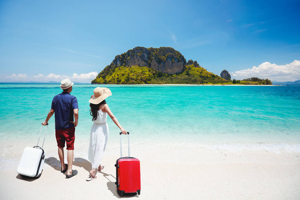 Asian coupl with a suitcase on the beach and looking hot air balloons, Travel &  Tourism business concept - Photo, Image