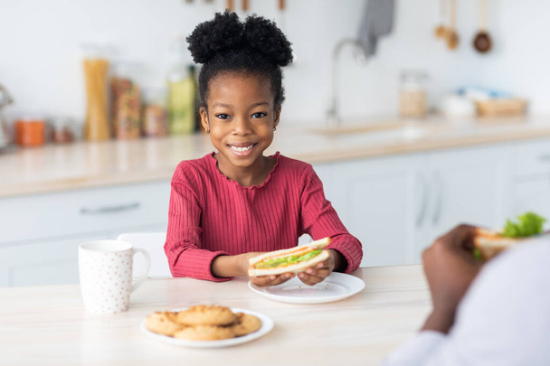 Pertty pequeña chica negra mostrando su sabroso sándwich - Foto, Imagen