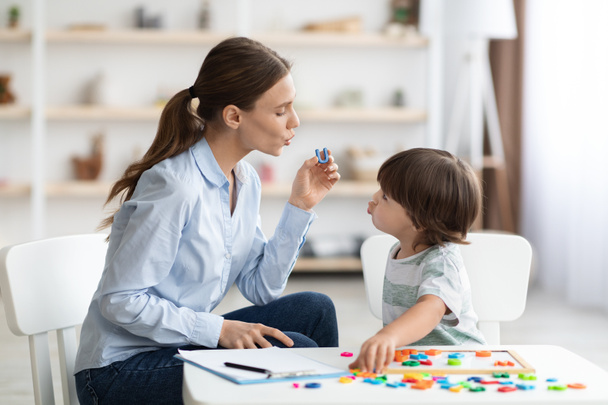 Mujer joven terapeuta del habla enseñando niño pequeño con defectos de pronunciación para decir sonido U durante el entrenamiento - Foto, imagen