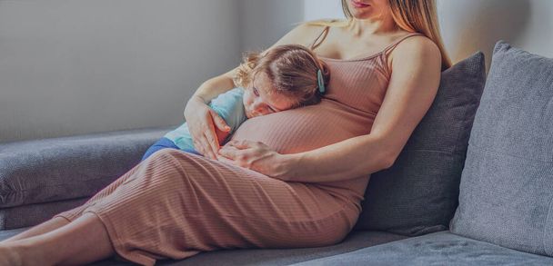 小さな赤ちゃんの女の子は母親の妊娠中の腹でリラックス-幼児と妊婦-ファミリーコンセプト - 写真・画像
