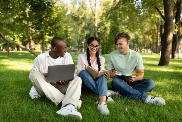 Група різноманітних студентів друзів вивчають, читають книги, використовують ноутбук і обговорюють щось в університетському містечку
 - Фото, зображення