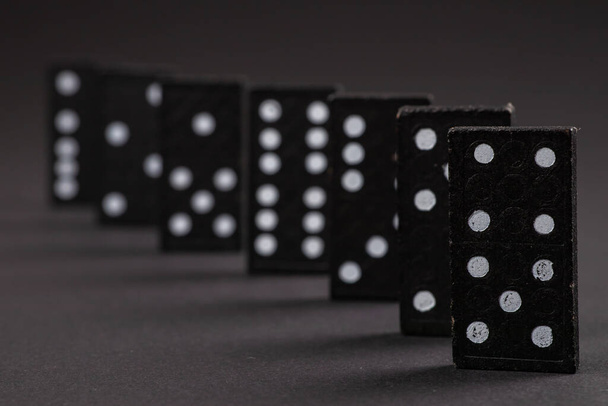 Černé domino na tmavém pozadí, roztroušené domino na šedém stole. Desková hra, Game night Dominos stolní hra. - Fotografie, Obrázek