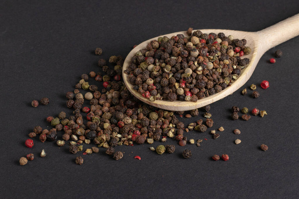 Mixed pepper in wooden spoon on dark background. - Photo, Image