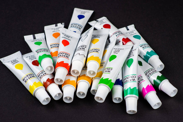 Kleurrijke acrylverf in tubes op donker. - Foto, afbeelding