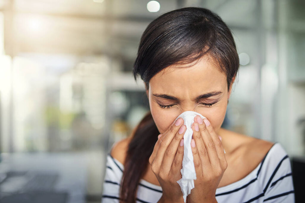 Alguém pode estar a apanhar uma constipação. Foto cortada de uma jovem empresária assoando o nariz com um lenço no escritório. - Foto, Imagem