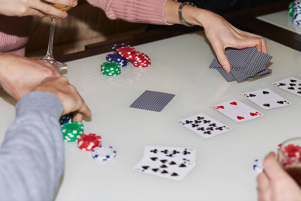 女性の手シャッフルカード。チップやカードでテーブルの上でポーカーをプレイの概念.シャンパンのグラスだ。ギャンブルの概念。瞬間を楽しむ、友人とデジタルデトックス。選択的焦点. - 写真・画像