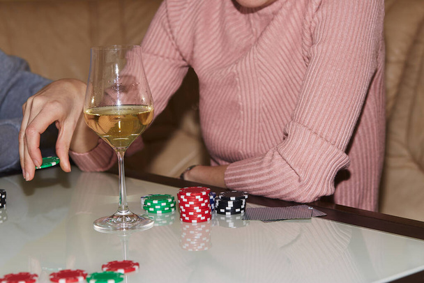 Kobieta ręka robi ruch z kości w grze w pokera. Karty, kości i kieliszki szampana. Szczera chwila. Poker tle styl życia fotografii. Ciesząc się chwilą, cyfrowy detox z przyjaciółmi - Zdjęcie, obraz