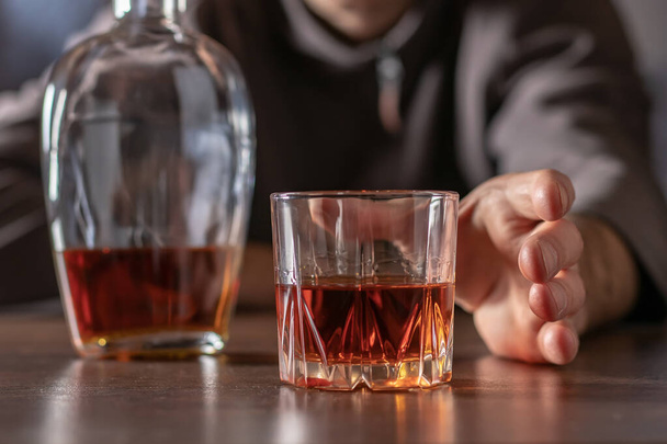 El alcoholismo, la adicción al alcohol y el concepto de la gente - el alcohólico masculino tira de su mano a un vaso de alcohol. - Foto, imagen