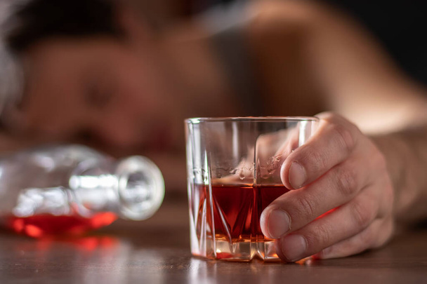 Alcolismo, dipendenza da alcol e il concetto di persone - alcolico maschile con un bicchiere di whisky sdraiato o dormire sul tavolo. - Foto, immagini