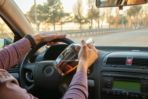 Hombre bebiendo alcohol mientras conduce en su coche
. - Foto, imagen