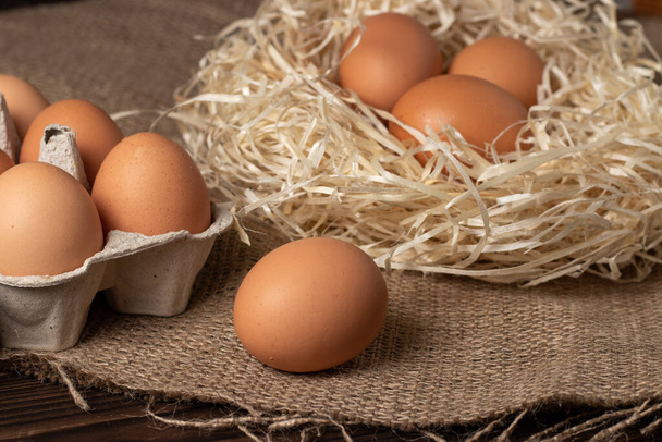 Brown eggs on burlap and wooden background. - Photo, Image