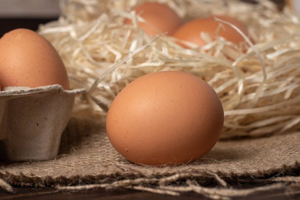 Brown eggs on burlap and wooden background. - Valokuva, kuva