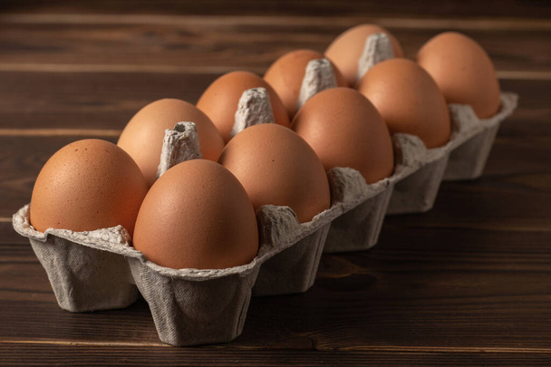 Feliz Páscoa. Ovos de Páscoa. Frango ovos castanhos closeup vista superior Em cima da mesa. Uma caixa de ovos castanhos frescos. Ovos de galinha orgânicos em uma caixa de ovos. - Foto, Imagem