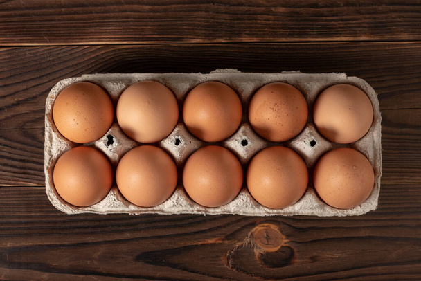 ハッピーイースター。イースターエッグ。鶏の茶色の卵がテーブルの上に閉じ表示されます。新鮮な茶色の卵のカートンの箱。卵箱の中の有機鶏の卵. - 写真・画像