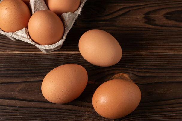 Feliz Pascua. Huevos de Pascua. Pollo huevos marrones primer plano vista superior En la mesa. Una caja de cartón de huevos marrones frescos. Huevos de pollo orgánicos en un cartón de huevo. - Foto, imagen
