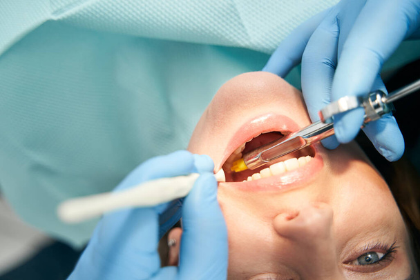 Woman receiving dental treatment in stomatology clinic - Фото, изображение