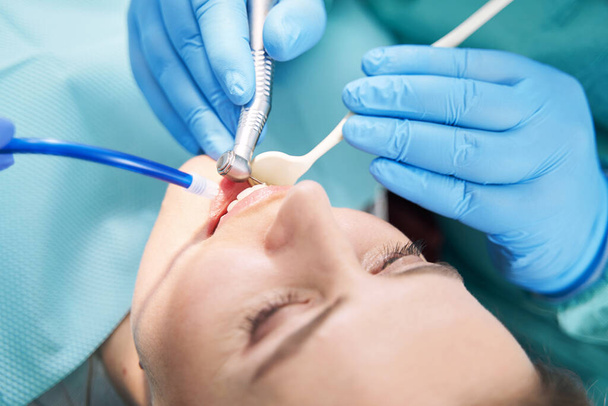 Dentist hands performing dental procedure with dental drill - Zdjęcie, obraz