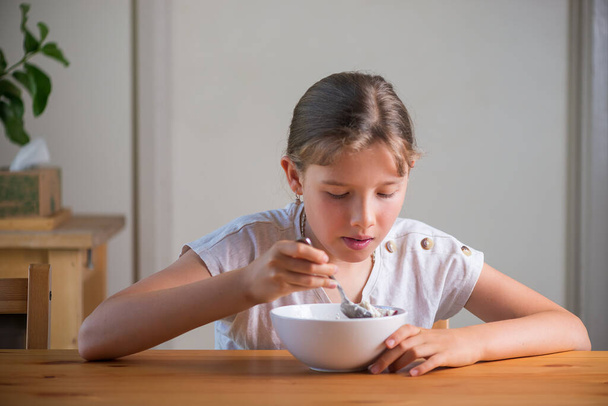 Blond tienermeisje dat ontbijtgranen eet. Lifestyle portret.  - Foto, afbeelding