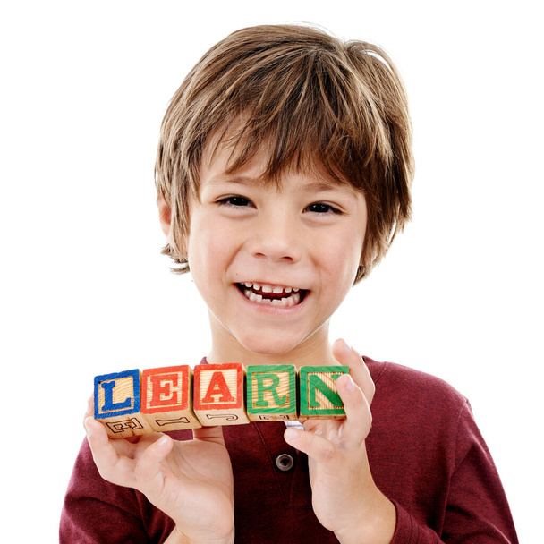 Hra je nejvyšší formou učení. Studio záběr roztomilý malý chlapec drží stavební bloky, které hláskují svět učit se na bílém pozadí. - Fotografie, Obrázek