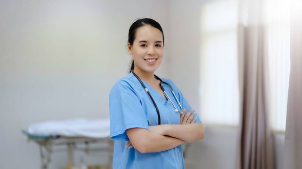 Молодая красавица-медсестра стоит и улыбается, глядя в камеру в больнице - Фото, изображение