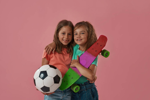 Hymyilevä pikkutytöt pallo ja rullalauta - Valokuva, kuva