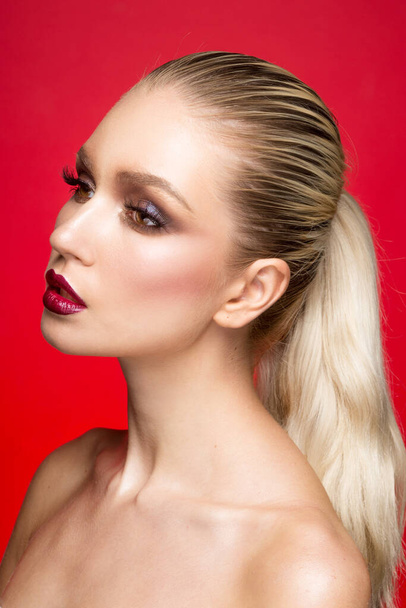 Profiel beauty portret van jong mooi model met perfecte make-up met blote schouders, over rode achtergrond. - Foto, afbeelding