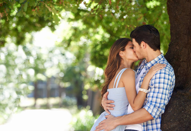 Больше ни с кем в мире... молодая пара целуется в парке. - Фото, изображение