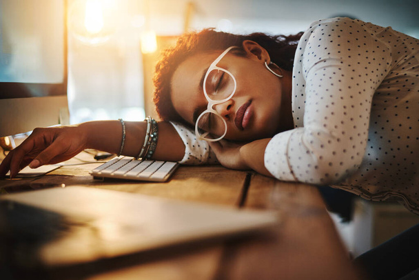 No llegó más allá de la medianoche. Fotografía de una joven mujer de negocios agotada durmiendo en su escritorio en una oficina moderna. - Foto, Imagen
