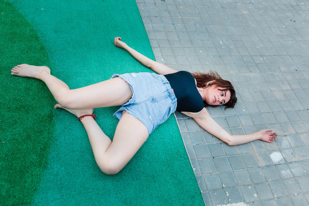 Молода пригнічена жінка лежить на землі на задньому дворі
 - Фото, зображення