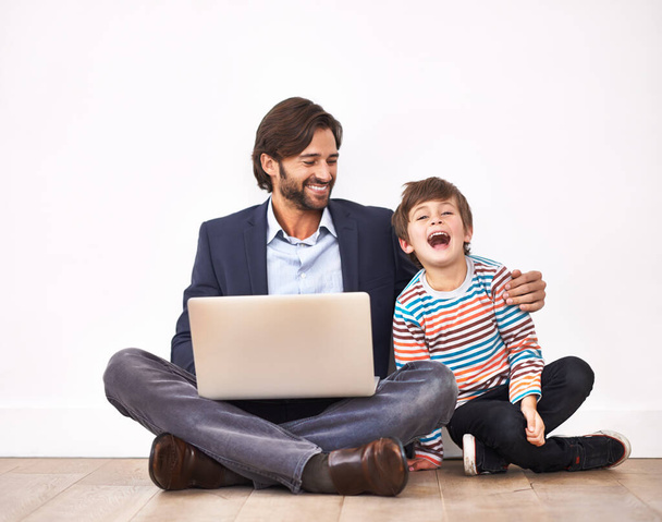 Насолоджуйтесь кумедними онлайн-відео. Батько і син сидять на підлозі з ноутбуком
. - Фото, зображення