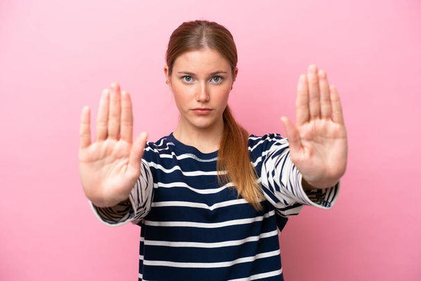 Joven mujer caucásica aislada sobre fondo rosa haciendo stop gesture y decepcionado - Foto, Imagen