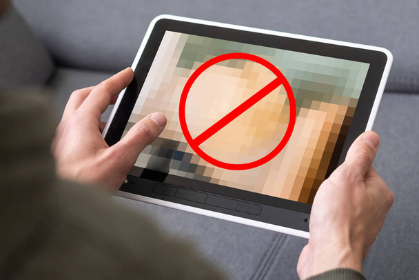 close-up van een jonge blanke man kijken naar een naakte vrouw in zijn tablet computer - Foto, afbeelding