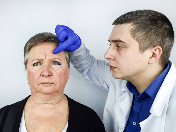 Une femme âgée lors d'une consultation avec un cosmétologue au sujet de l'élimination des rides liées à l'âge sur son visage. Le médecin explique quelles procédures seront effectuées. Contourage du visage. - Photo, image