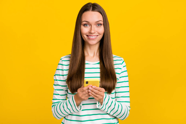 Photo of sweet shiny lady dressed striped shirt chatting modern gadget isolated yellow color background - Φωτογραφία, εικόνα