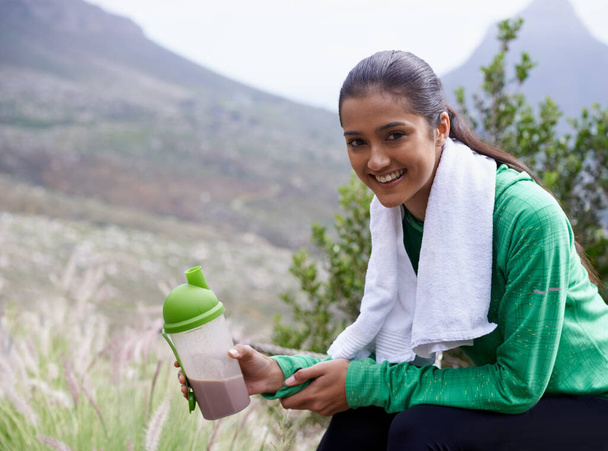 Taking a break from her hike. Portrait of an attractive young woman holding a sports drink outdoors. - Foto, afbeelding