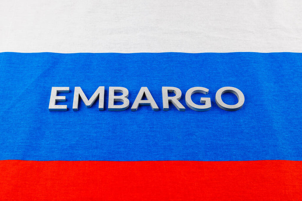 the word embargo laid with silver metal letters on russian tricolor flag - Fotó, kép