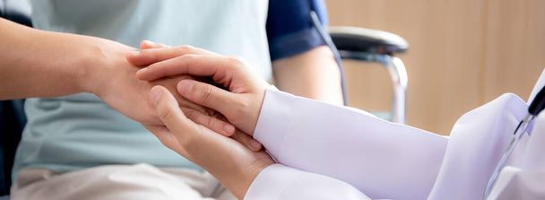 Szoros kéz az orvos nő ösztönzi a beteg vezető ülő kerekesszék a kórházban, orvos vigyázni, és kézen fogva vigasztalására idős, diagnosztikai betegség és betegség, orvosi fogalom. - Fotó, kép