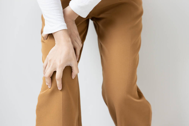 Aziatische jonge vrouw met knie gewrichtspijn of knieblessure probleem, concept van knie gezamenlijke chirurgie of orthopedie behandeling - Foto, afbeelding