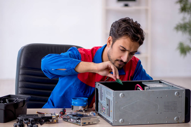 Молодой ремонтник-мужчина ремонтирует компьютер - Фото, изображение
