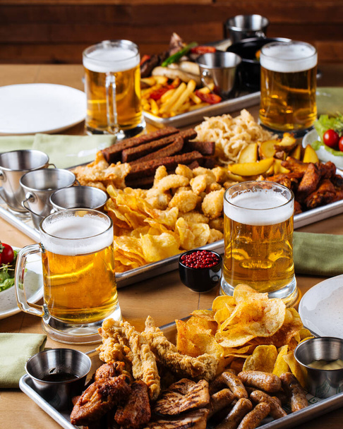 Table set with beer and salty snacks - Foto, afbeelding
