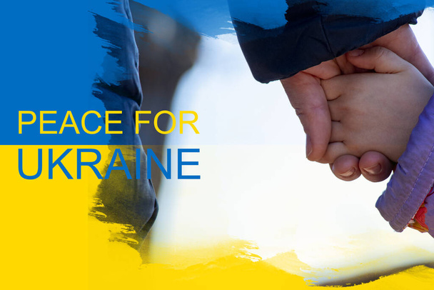 Matka trzyma małą dziewczynkę za rękę na tle żółto-niebieskiej flagi Ukrainy. Pokój na Ukrainie, zatrzymać wojnę 2022 - Zdjęcie, obraz