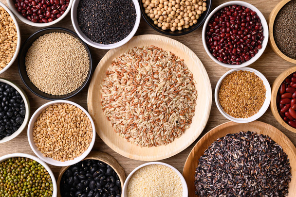 Varios cereales, granos, frijoles, legumbres y semillas en cuenco sobre fondo de madera, ingredientes alimentarios, vista superior de la mesa - Foto, imagen