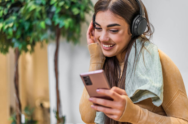 Happy caucasian girl, turning the music on her phone, while using headphones. - Foto, Bild