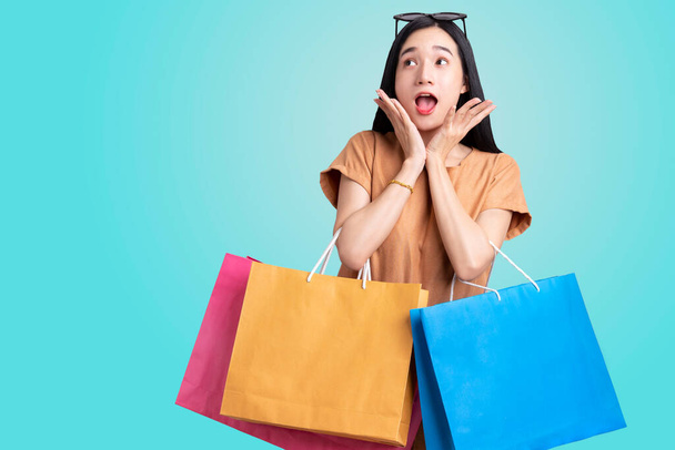 Portret aziatische vrouw dragen kleurrijke boodschappentassen op geïsoleerde blauwe achtergrond, zomer verkoop concept, Jonge vrouw geniet gelukkig met winkelen - Foto, afbeelding