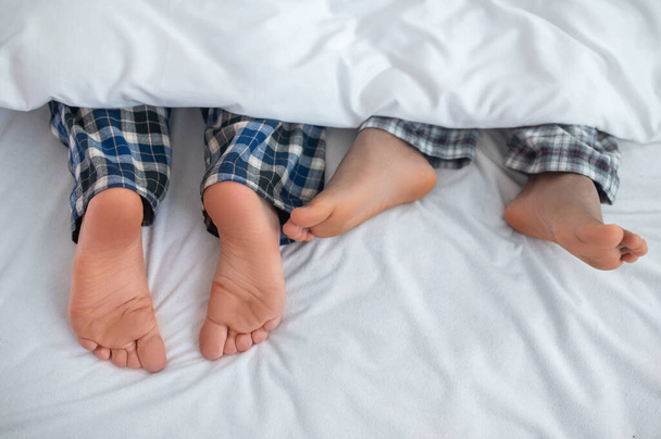 Gay couple with bare feet resting in their bedroom - Photo, Image