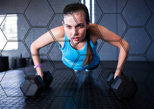 Hexagonal shapes pattern against caucasian fit woman performing push up exercise with dumbbells. sports, fitness and technology concept - Φωτογραφία, εικόνα